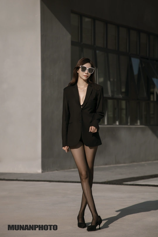 一个穿着黑色西装和太阳镜的年轻女子走在街上