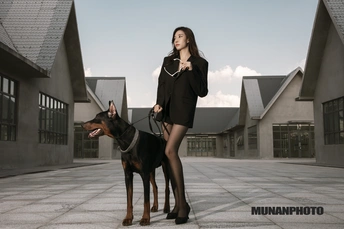 一个美丽的年轻女子站在一只黑棕色的狗旁边