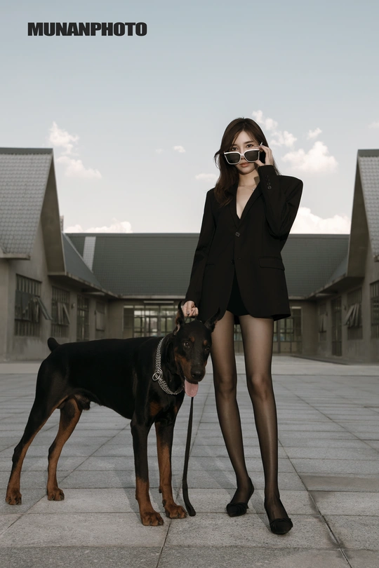 一位站在一只黑棕色狗旁边的女士