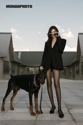 一位站在一只黑棕色狗旁边的女士