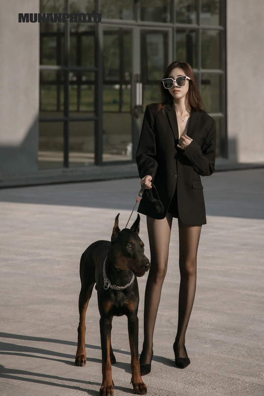 一个穿着黑色西装的年轻女子抱着一条黑色狗链。