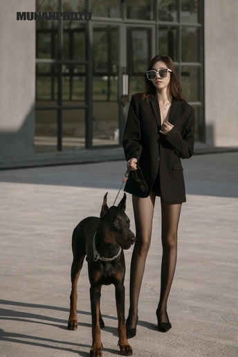 一个穿着黑色西装的年轻女子抱着一条黑色狗链。