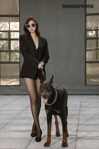 一位女士牵着一条黑狗