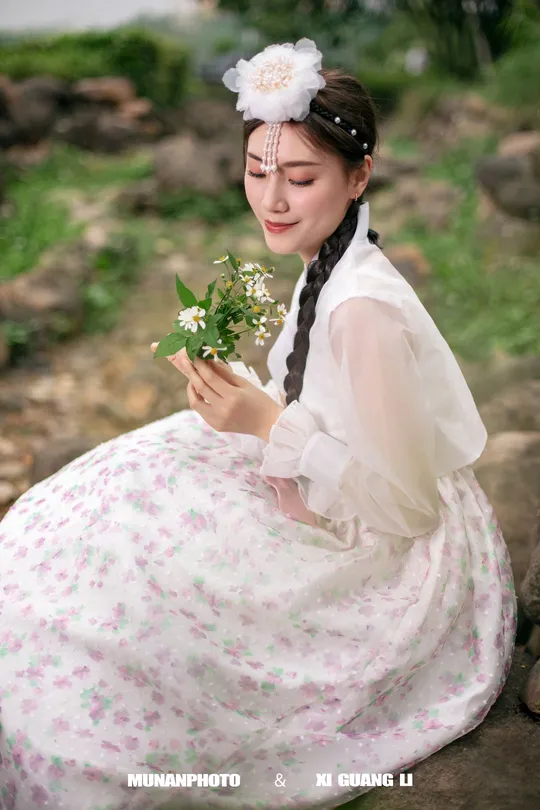 一位穿着传统服装的年轻女子抱着白色花朵