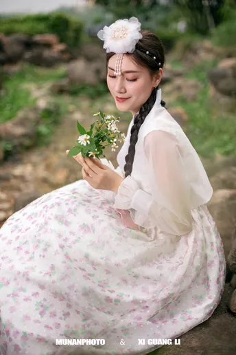 一位穿着传统服装的年轻女子抱着白色花朵