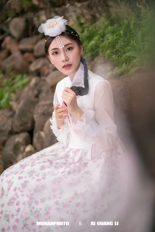 一位穿着传统裙装 裙装上有白色花朵的少女 身着粉色裙子。