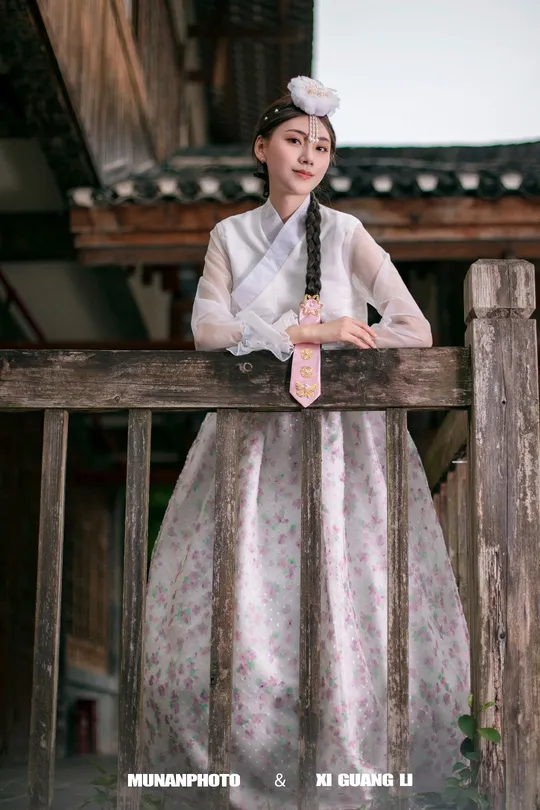 一位穿着costume的女性站在木栅栏旁边