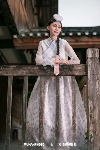 一位穿着costume的女性站在木栅栏旁边