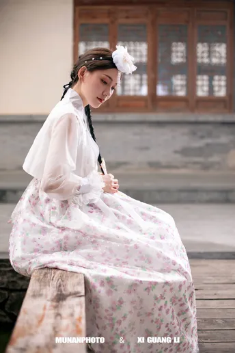 一位身着中国传统服装的年轻女子坐在石头长凳上