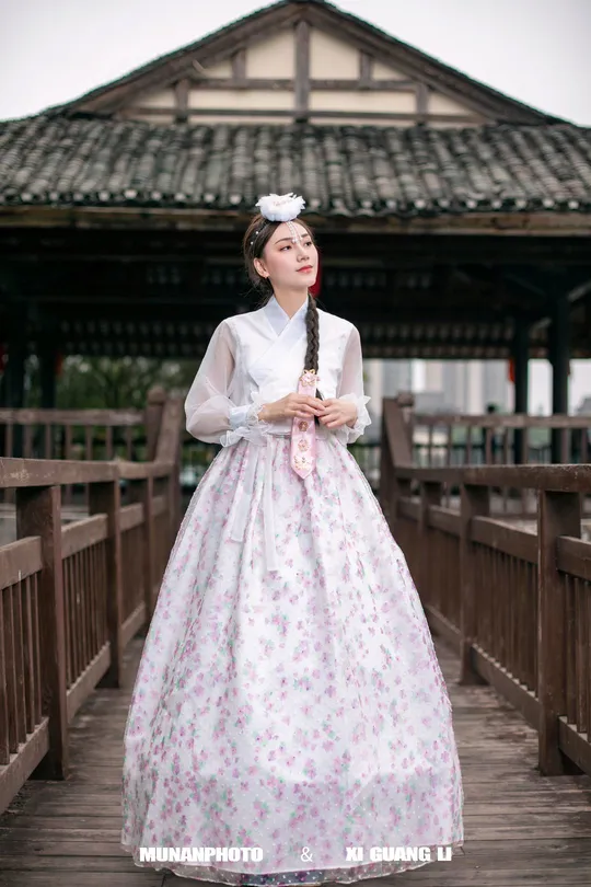 一位穿着传统服装的年轻女子站在木桥上