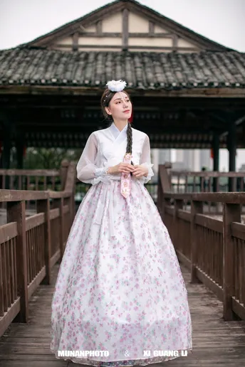 一位穿着传统服装的年轻女子站在木桥上