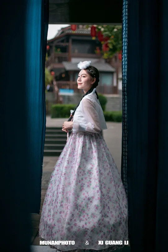 一位穿着连衣裙的女人站在窗户前