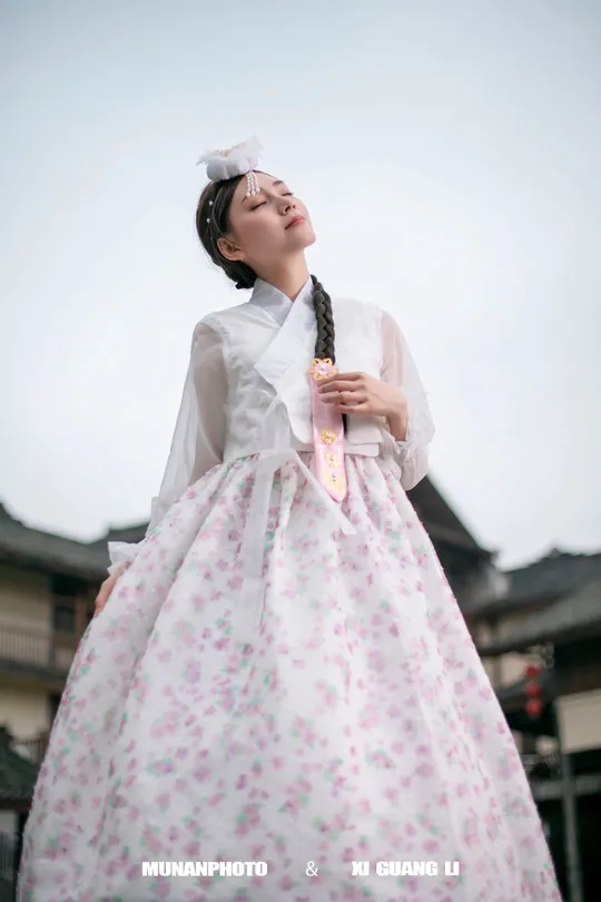 一位穿着传统服装的女性戴着粉色雨伞。