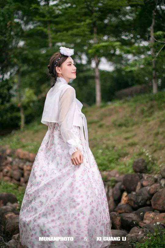 一位穿着白色连衣裙站在岩石上的女人