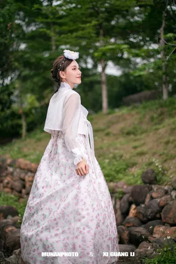 一位穿着白色连衣裙站在岩石上的女人