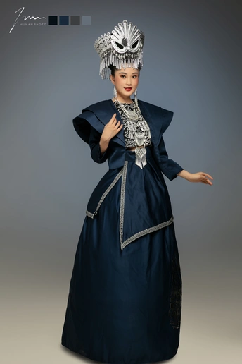 一位穿着传统服装的年轻女子在灰色背景上摆姿势