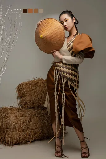 一位穿着costume的年轻女子手持一顶帽子站在一捆干草前面