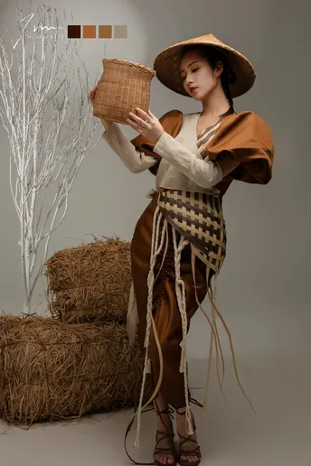 一位穿着服装的女性 举着帽子 站在麦堆前摆姿势