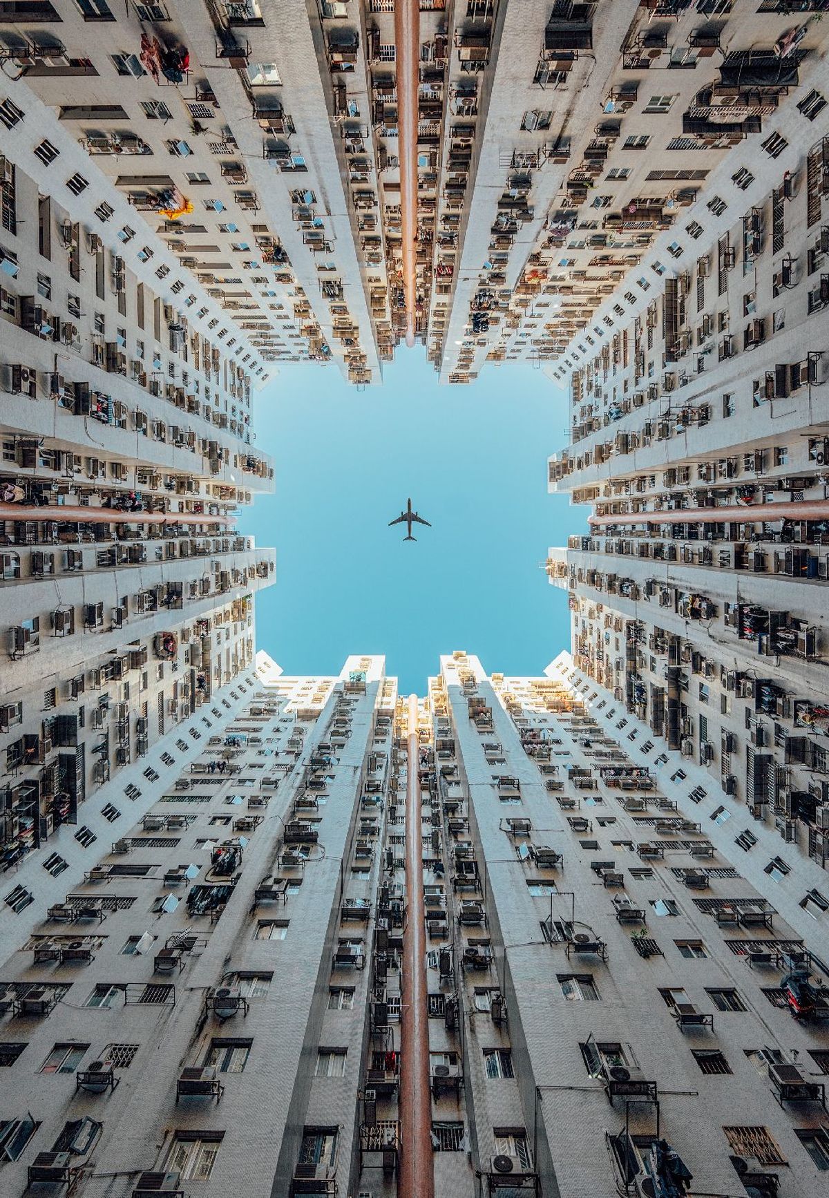 从高空拍摄的拥有高楼大厦的城市和一架飞机在蓝天中飞行的照片。