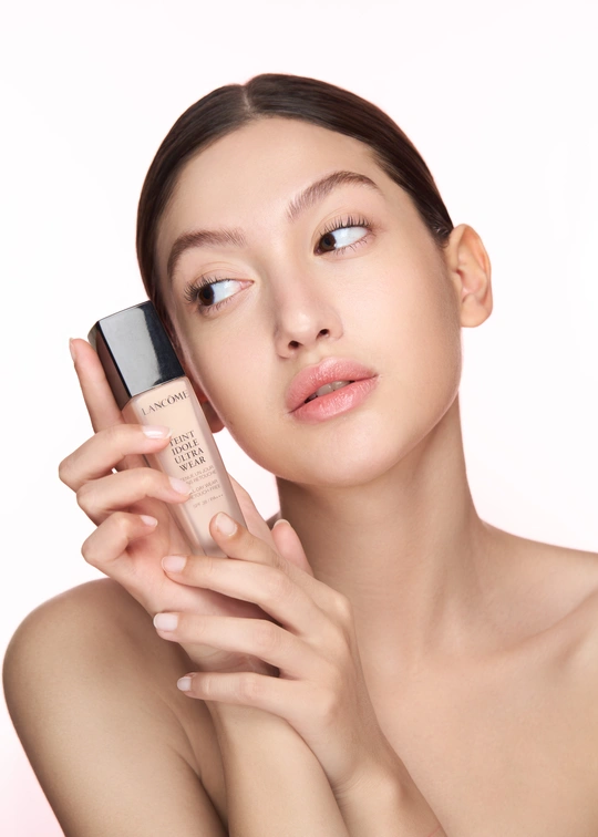 一位年轻美丽的女子将一瓶奶油涂在脸上