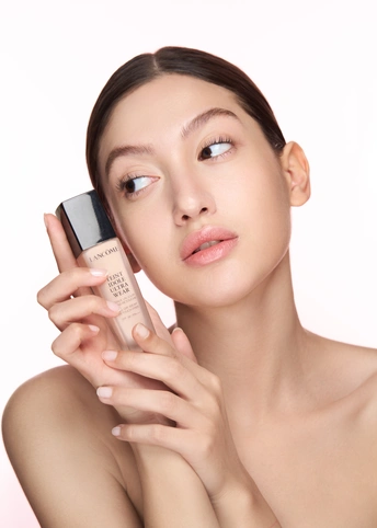 一位年轻美丽的女子将一瓶奶油涂在脸上