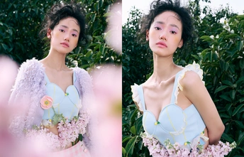 一位穿着蓝色连衣裙的女子在紫花丛前摆姿势拍照