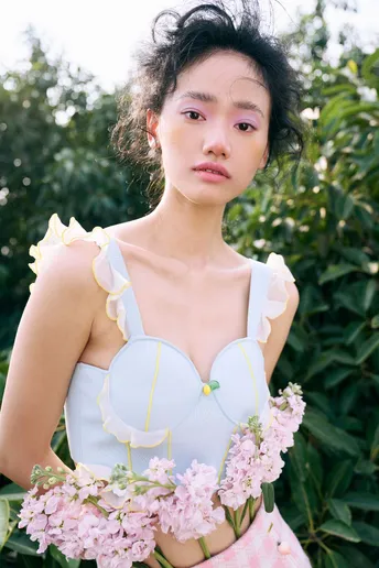 一位穿着蓝白色连衣裙 拿着粉色花朵的女性