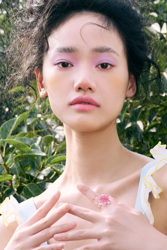 一位手上戴着戒指 前面有朵粉色花的女士