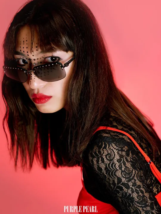 一位穿着红色连衣裙、黑色太阳镜、黑色面罩的女孩 背景为粉红色。