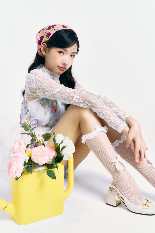 一个穿着连衣裙的年轻女子坐在一个带有粉色花朵的黄色水壶旁边