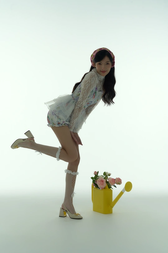 一位穿着白色连衣裙和白色鞋子的年轻女子 交叉双腿 手持黄色水壶。