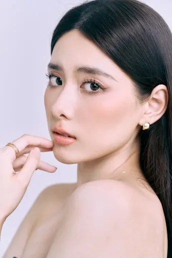 一位美丽的年轻女子戴着一只耳环和一只项链 背景为白色。