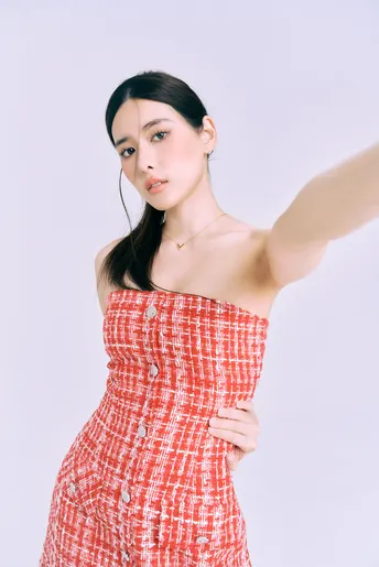 一位穿着红白相间格子裙子的模特 她的手臂搭在肩膀上。