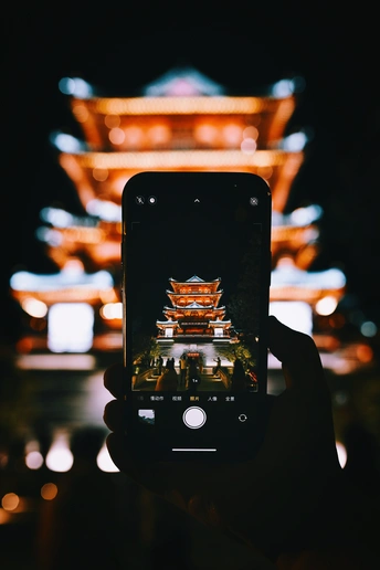 一个人手里拿着手机在晚上拍照