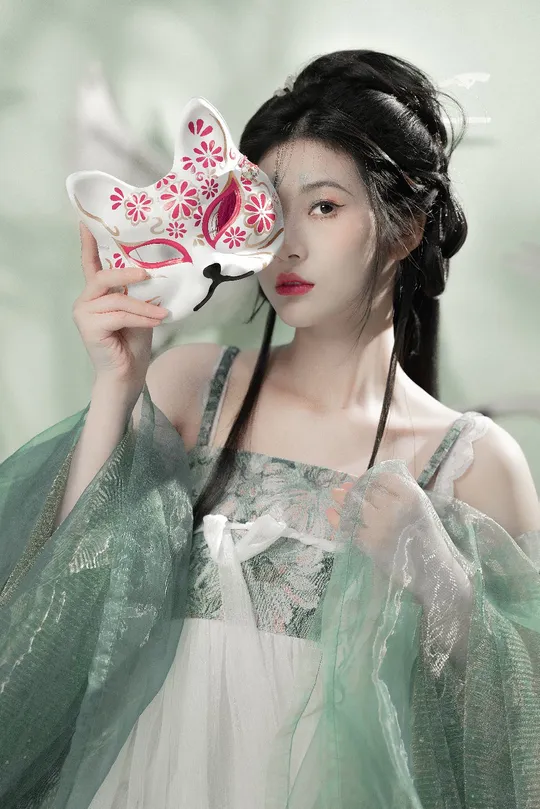 一位穿着绿色连衣裙的女士拿着面具