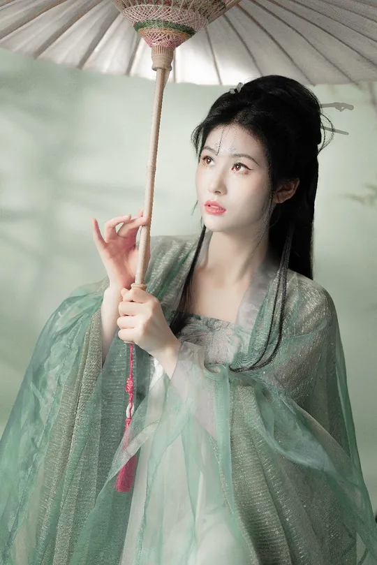 一位穿着绿色连衣裙 拿着雨伞的女人