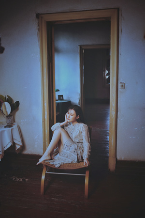 一个穿着连衣裙的年轻女子坐在房间的木椅上