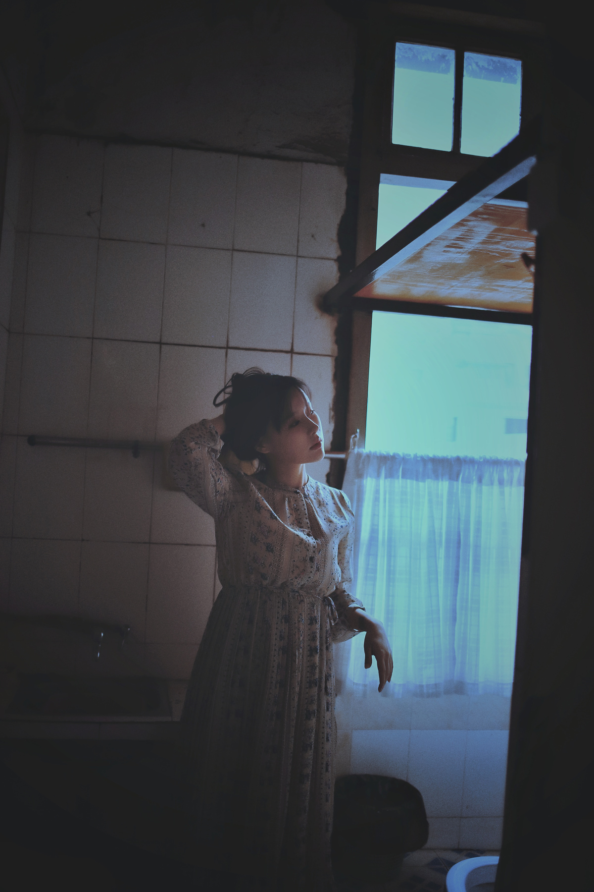 一个年轻的女人站在一个黑暗的房间里望着窗外