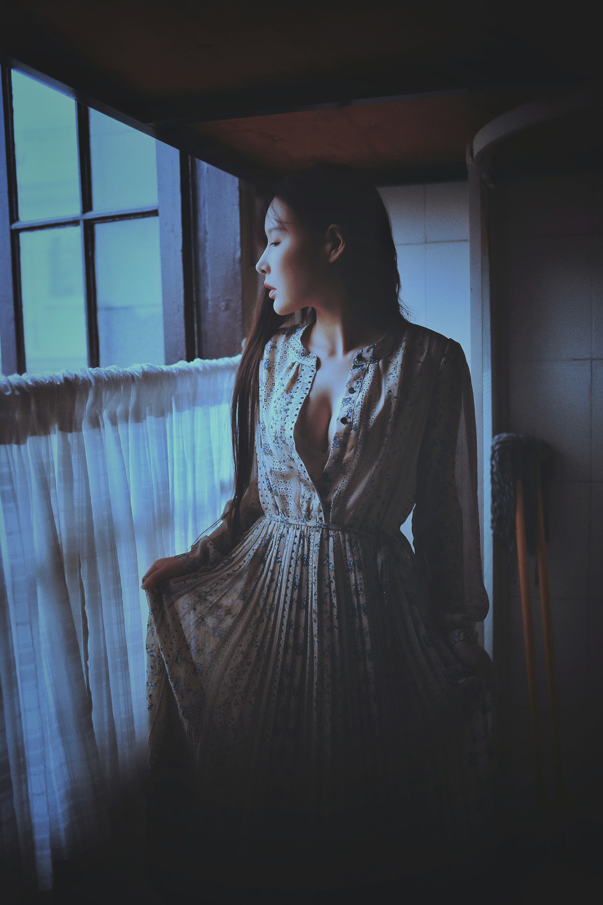 一个穿着连衣裙的女人站在窗户旁边