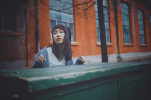 一位年轻女子坐在一栋楼前的绿色桌子旁