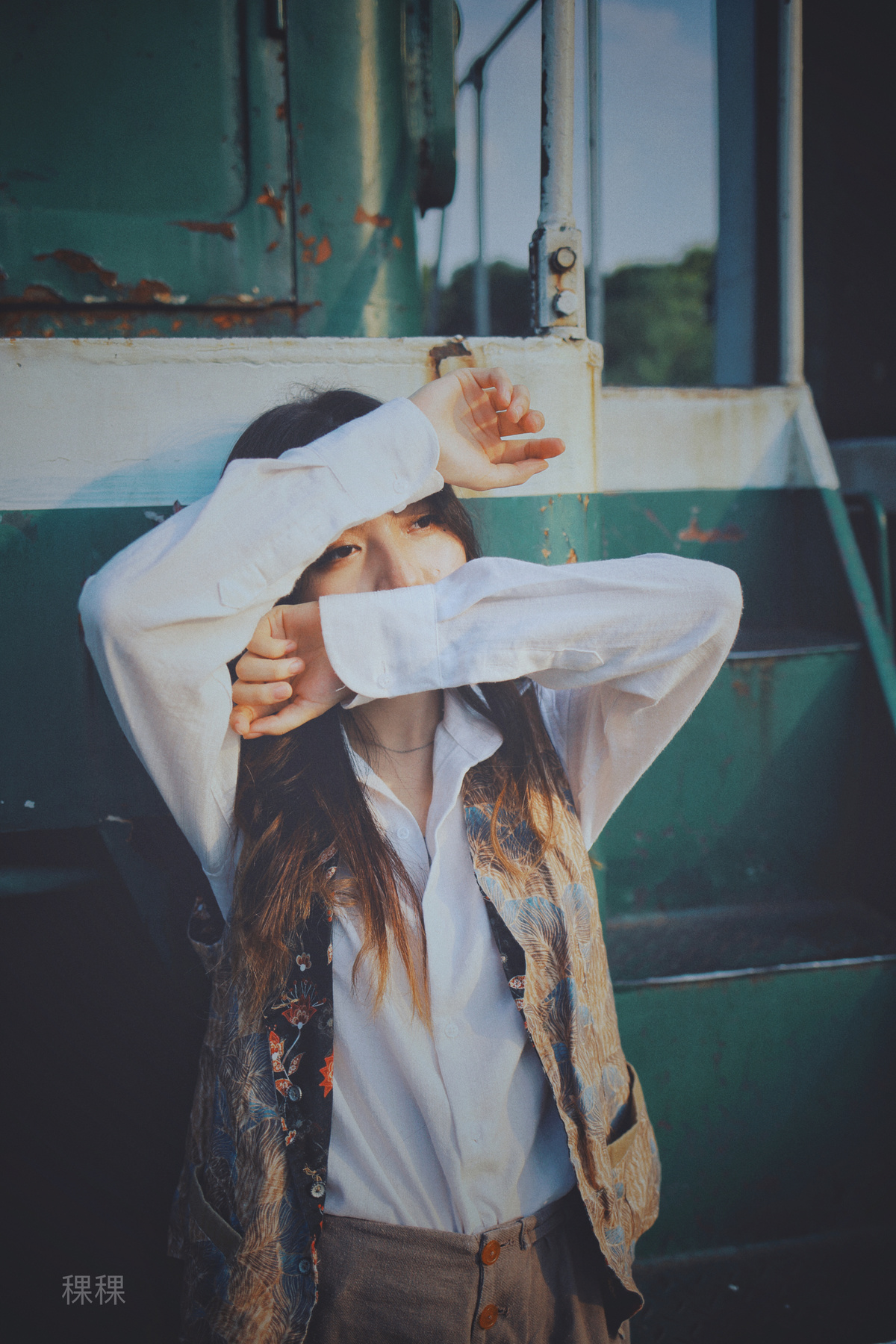 一位身穿白衬衫的年轻女子站在火车旁 双手捂着眼睛 掩面