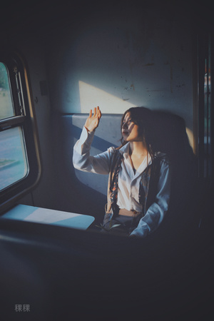 一个坐在火车上的年轻女子举起手看着窗外
