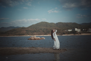 一位穿着白色连衣裙站在水边的女人