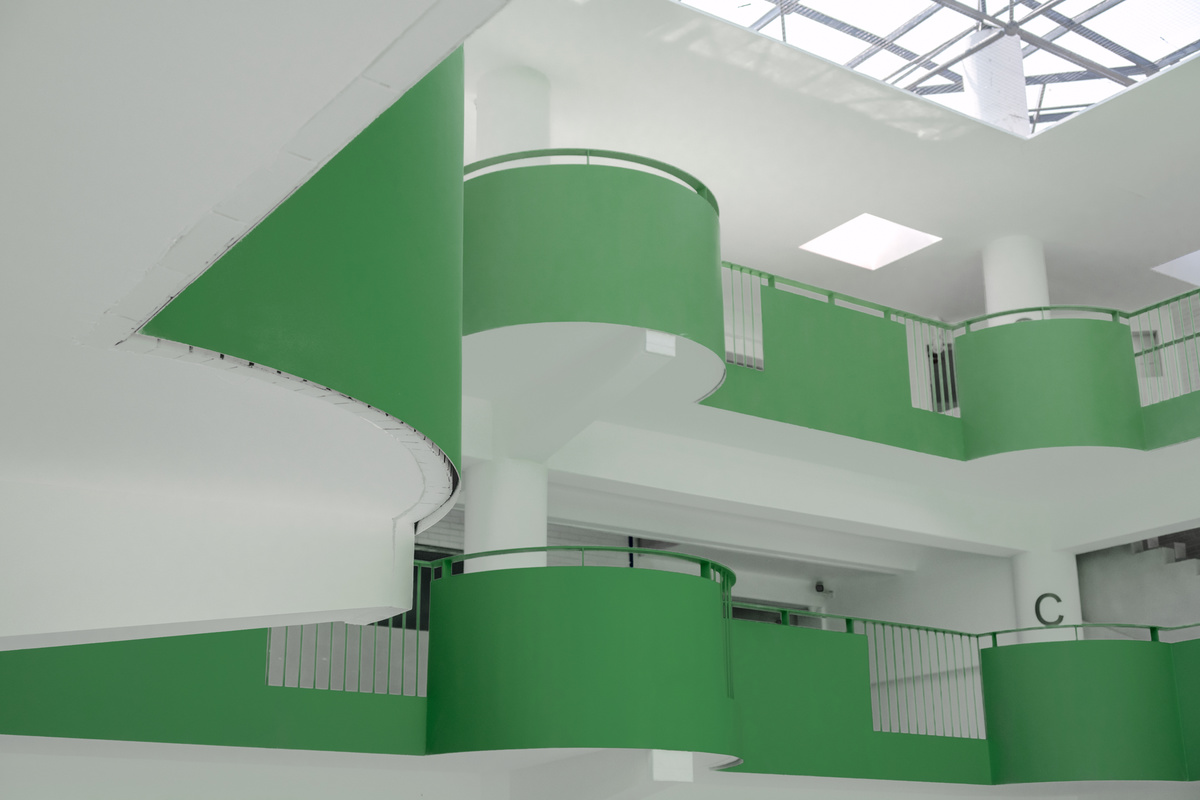 一个大白色的房间 有绿色的楼梯和阳台