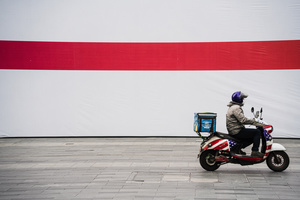 一个男人骑在一辆摩托车上 前面有一面巨大的红色和白色旗帜。