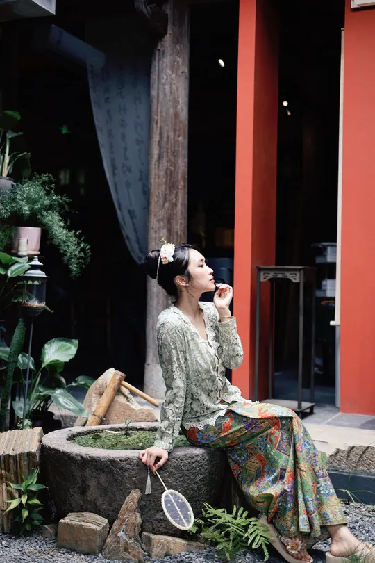 一位女子拿着网球拍坐在雕像上