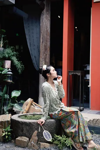 一位女子拿着网球拍坐在雕像上