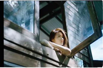 一位年轻女子站在阳台上 透过建筑物的窗户向外看。
