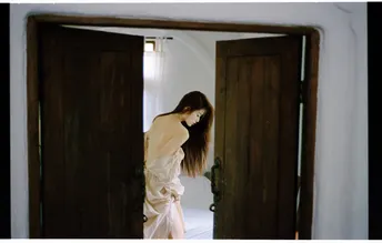 一位穿着白色长袍的女子站在一个房间的镜子前