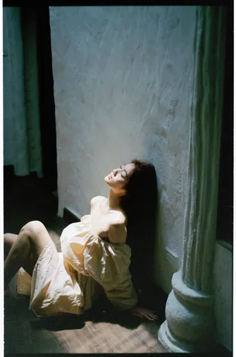 一个穿着白色连衣裙的女人躺在有柱子的房间里